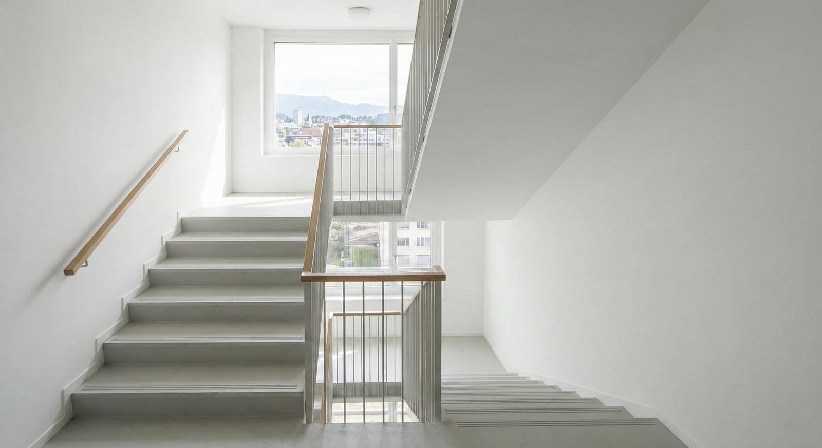Frisch gestrichenes Treppenhaus mit weissen Wänden und Holzgeländer