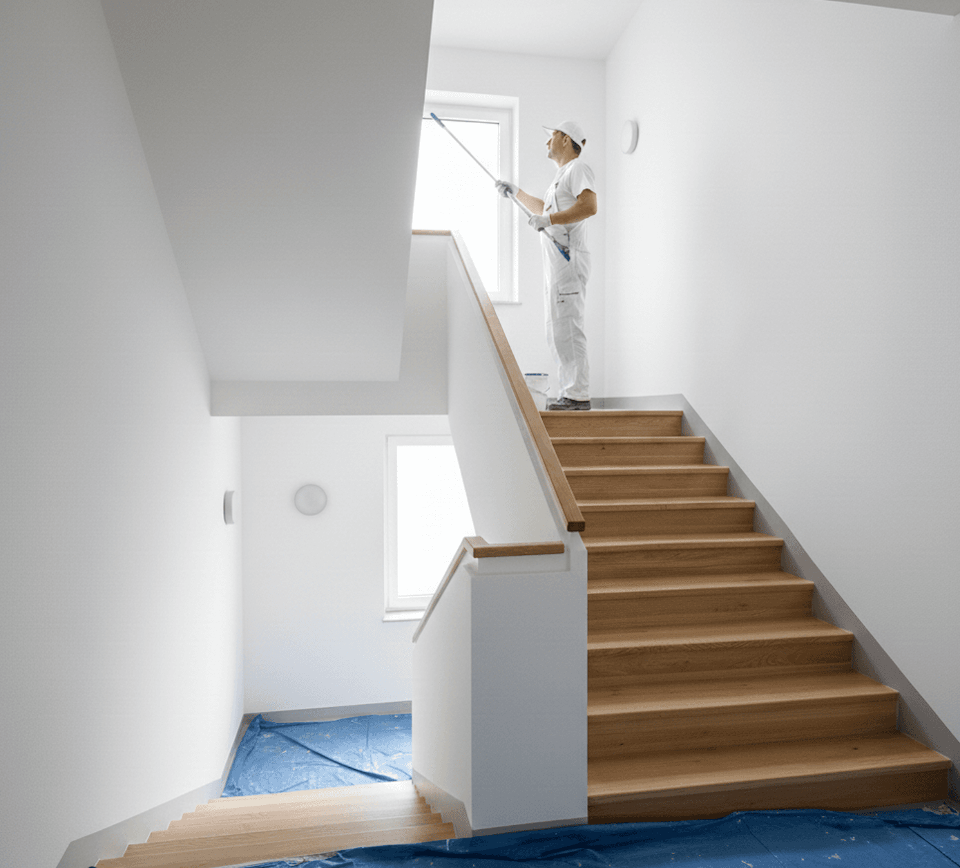 Maler lackiert Holzgeländer im Treppenhaus