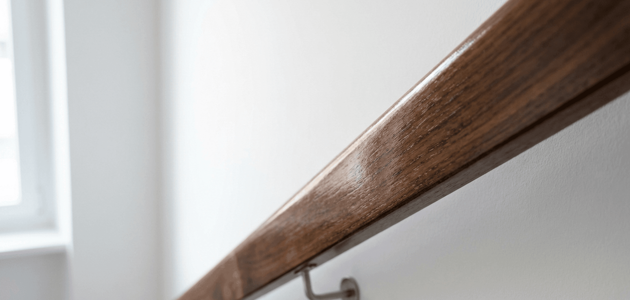 Weisses Treppenhaus mit lackiertem Geländer und Sockelleiste